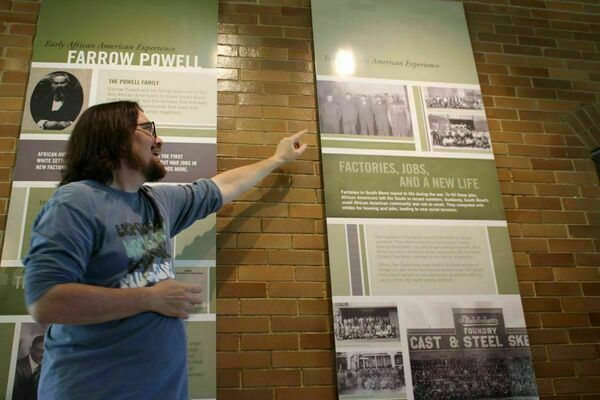 The Civil Rights Heritage Center's George Garner discusses South Bend's fraught past. 
A person stands indoors in front of a wall display with historical text and photographs. He is  pointing at one of the mounted posters.
