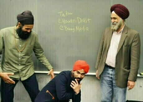 An image of three adult male-presenting individuals, all wearing headscarves. On the right is Professor Nirvikar Singh, dressed in an army green jacket over a white shirt, paired with a burgundy headscarf. Beside him are Sikh hip-hop artists Baagi and Hoodini (Gunjiv and Jagmeet Singh), captured in March 2015.