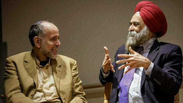 Professor Nirvikar Singh (R) wearing a black suit and white shirt with red head tie shares his thoughts with Professor Waleed El-Ansary wearing a beige suit and cream shirt at the Ansari Institute's second annual Book Prize on World Religions.