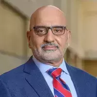 Headshot of a man, Ebrahim Moosa. He wears a boldly striped tie and eyeglasses and looks directly into the camera with a slight smile.