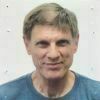 Portrait of a Caucasian man who is looking directly at the camera and smiles. He is wearing a light blue shirt.
