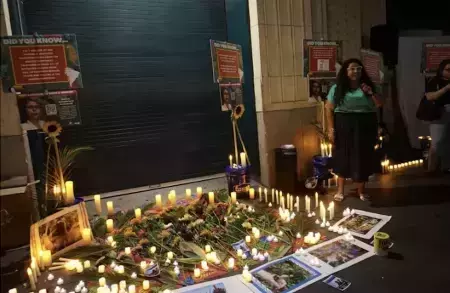 A display of candles and flowers on the floor in front of two posters.